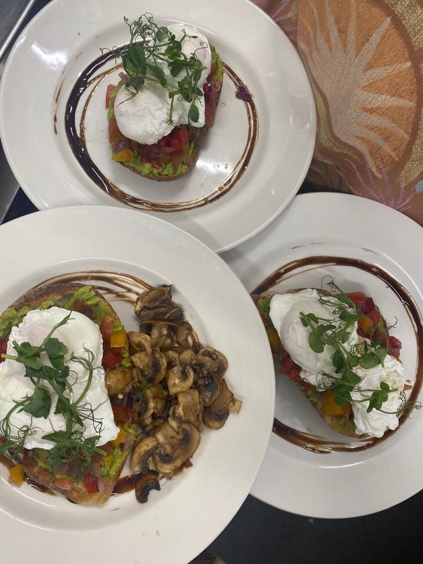Three plates of avocado toast with poached eggs, pea shoots and balsamic swirls