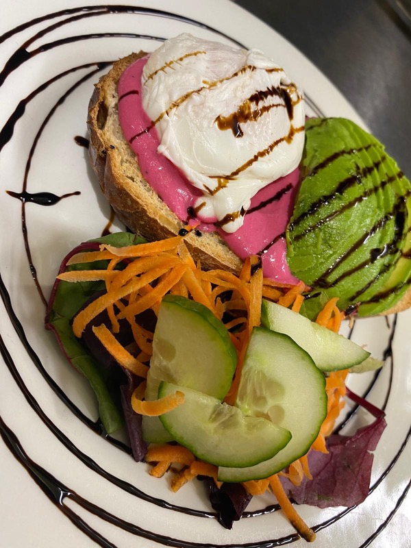 Poached egg on vivid pink beetroot hummus toast with avocado